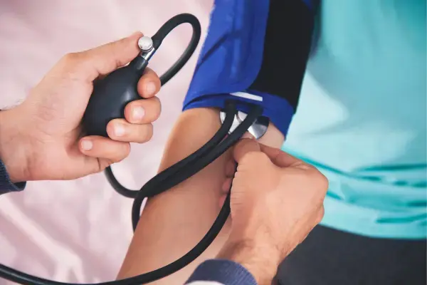 Médico aferindo pressão de pessoa (Fonte: Canva)