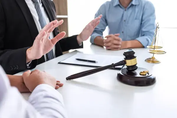Três pessoas conversando ao redor de mesa com malhete (Fonte: Canva)