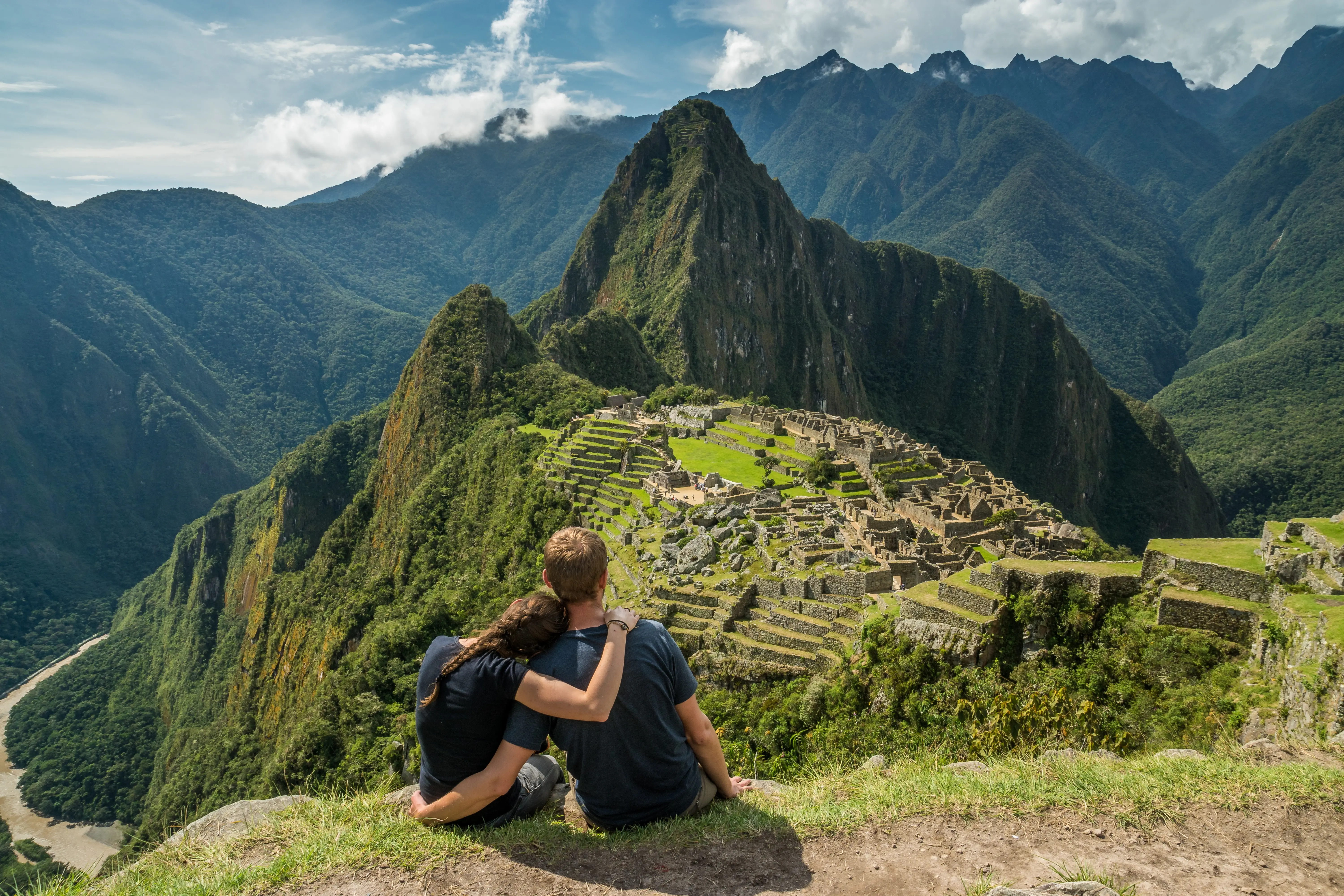 vista do alto de macchu pichu e um casal sentado na pedra