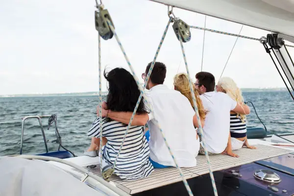 4 pessoas abraçadas sentadas em barco olhando para o mar (Fonte: Adobe Stock)