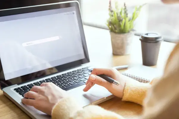 Mulher em frente a notebook (Fonte: Canva)