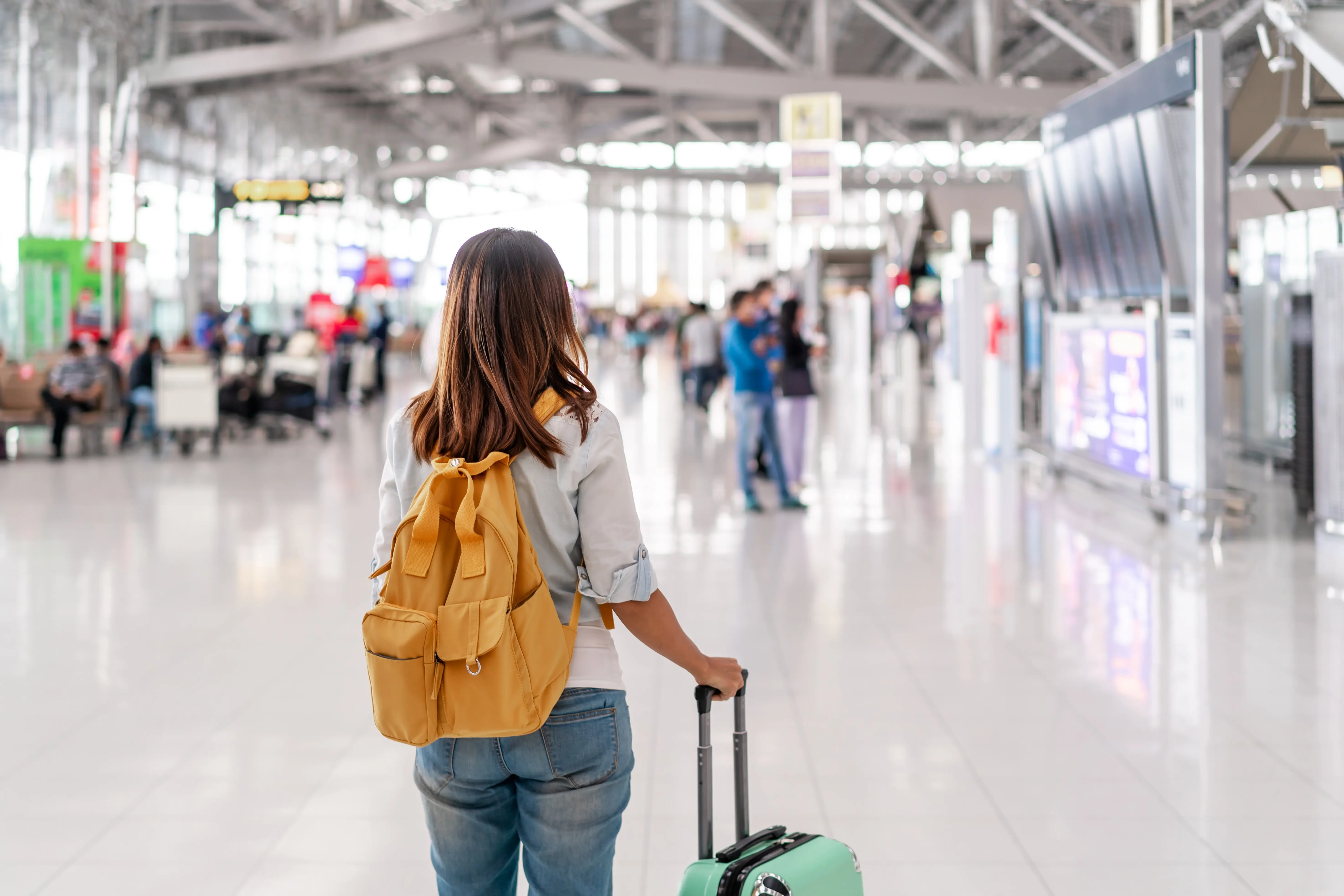 Mulher segurando mala em aeroporto (Fonte: Adobe Stock)