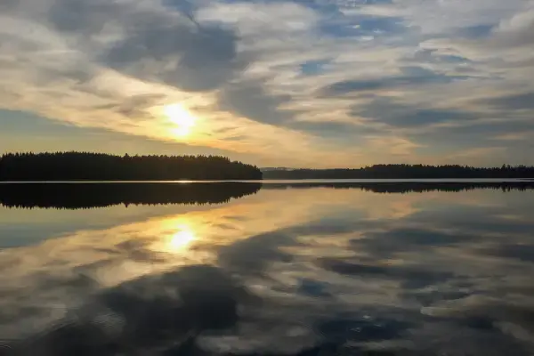 Sol refletindo em lago na Finlândia