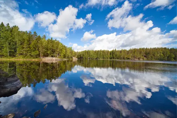Nuvens e céu refletindo em lago, na Finlândia