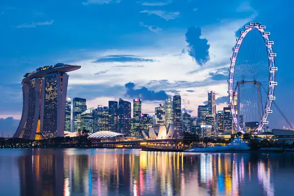 Vista de Singapore Flyer e Marina Bay Sands e luzes da cidade refletidas no mar
