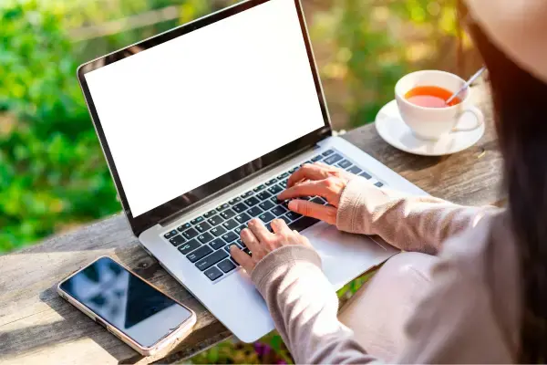 uma mulher mexendo em seu laptop ao ar livre