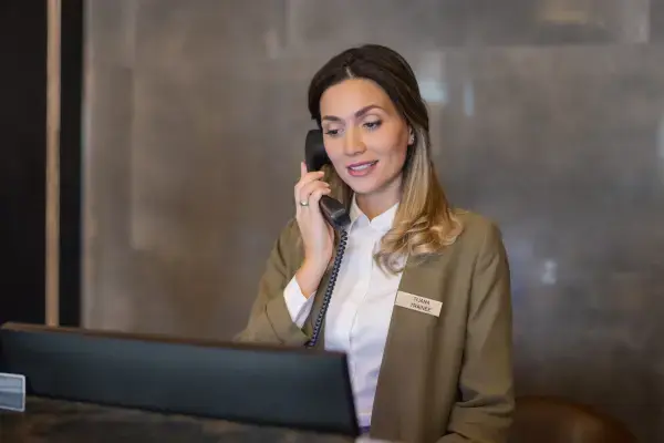 Mulher concierge falando no telefone (Fonte: Canva)