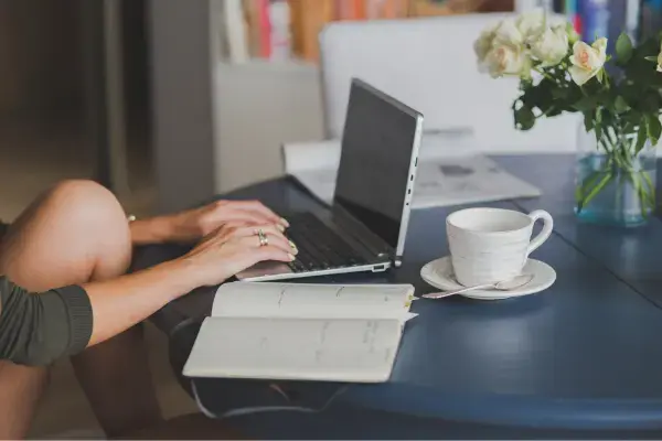 notbook em cima da mesa enquanto uma pessoa mexe