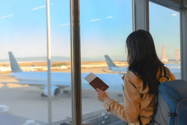 Mulher de mochila observando aviões pela janela