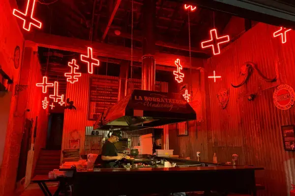 Bar noturno em São Paulo com iluminação vermelha em neon, balcão central e ambiente fechado, frequentado por pessoas à noite.