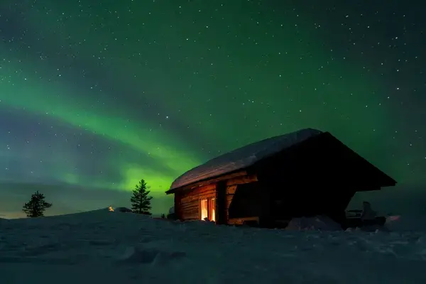 Aurora boreal sobre cabana em paisagem nevada do norte da Europa