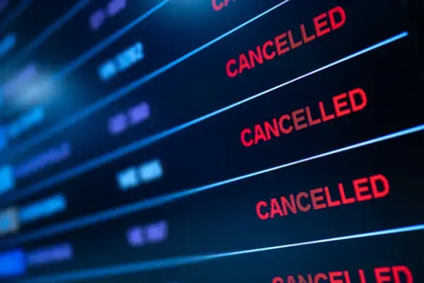 Painel de aeroporto exibindo voo cancelado durante viagem na baixa temporada