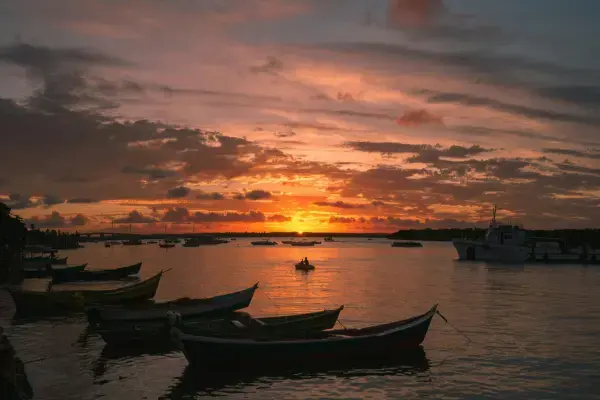 Paisagem com por do sol e barcos refletidos no mar