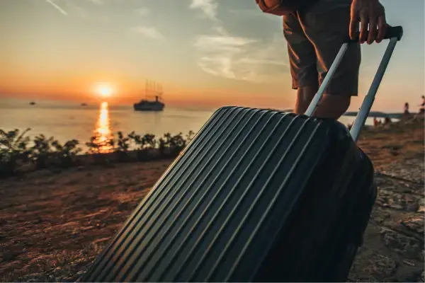 Homem carregando uma mala com paisagem de praia ao fundo