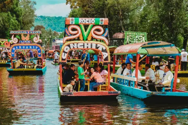 Turistas em trajineras coloridas navegando pelos canais de Xochimilco.