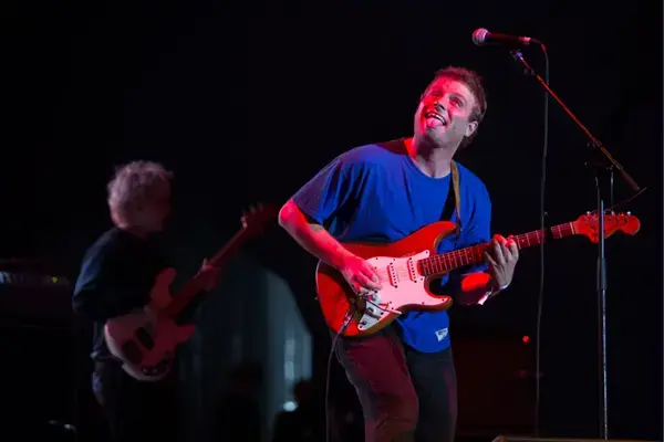 Mac DeMarco tocando guitarra durante Lollapalooza 2018 com iluminação colorida.