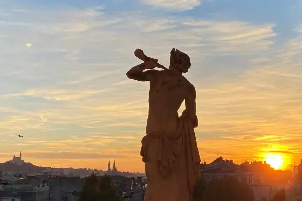 Estátua em Marselha, com visão para o por do sol na cidade