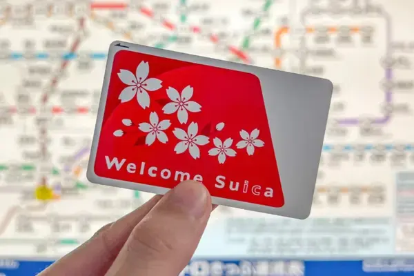 Pessoa segurando cartão Suica em frente a mapa do metrô japonês