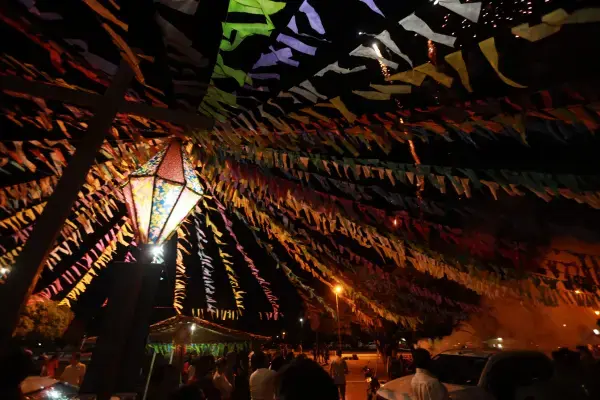 Bandeirinhas coloridas e balão iluminado decorando uma festa junina à noite