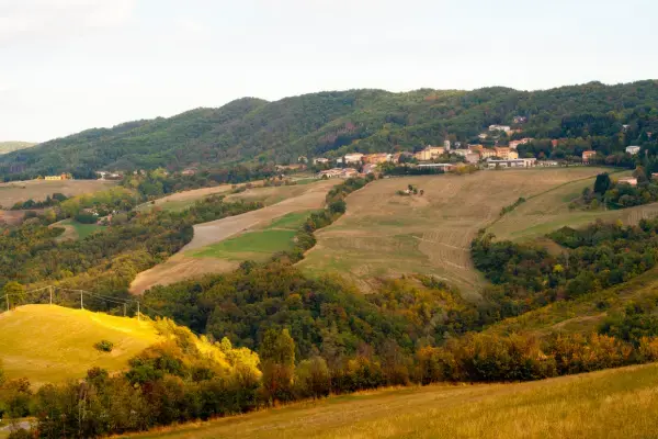 Paisagem do interior europeu com vilarejo e colinas verdes ao fundo.