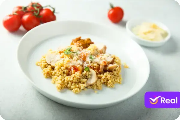 Prato grande de cuscuz marroquino coberto com um ensopado de legumes coloridos, como cenoura e abobrinha, e pedaços de carne.