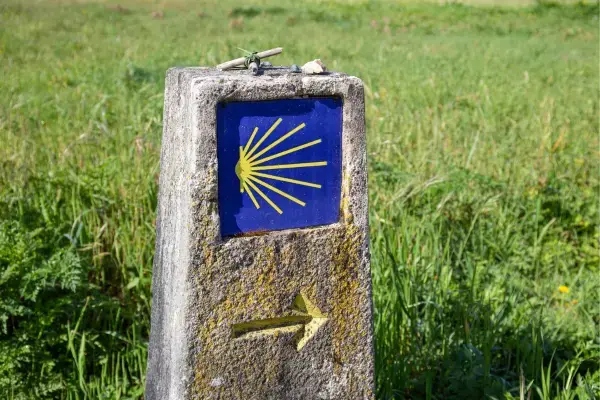 Marco de pedra com concha e seta amarela indicando o Caminho de Santiago na Espanha