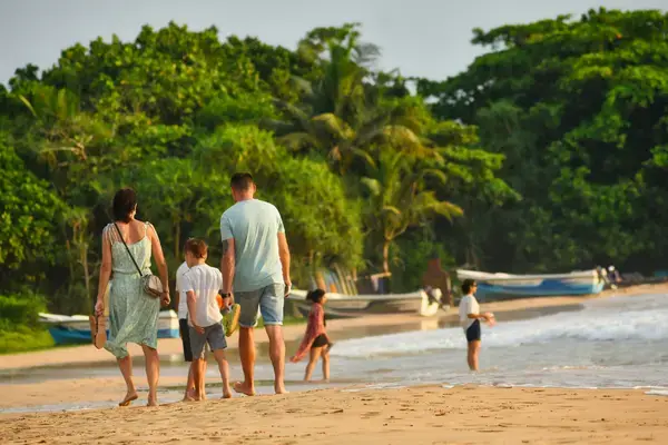 Família na praia em dia de sol no Réveillon com bagagem de viagem