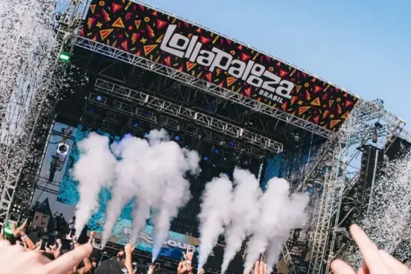 Palco principal do Lollapalooza Brasil durante show, com efeitos de fumaça, estrutura metálica e público com braços levantados no Autódromo de Interlagos.