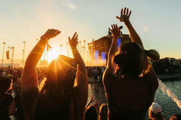 Público de braços erguidos em um festival de música ao entardecer
