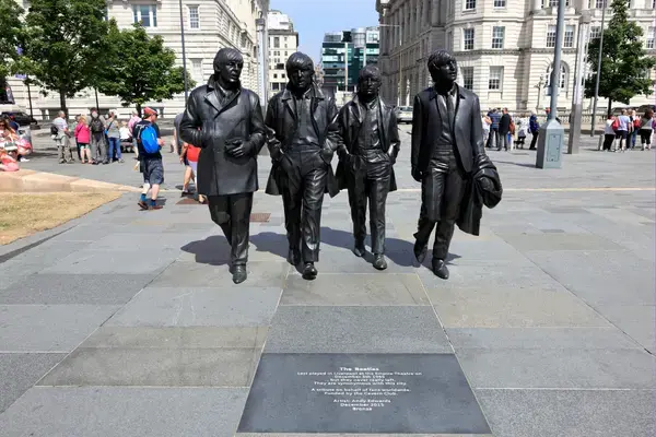 Estátua dos Beatles no Pier Head em Liverpool com turistas tirando fotos