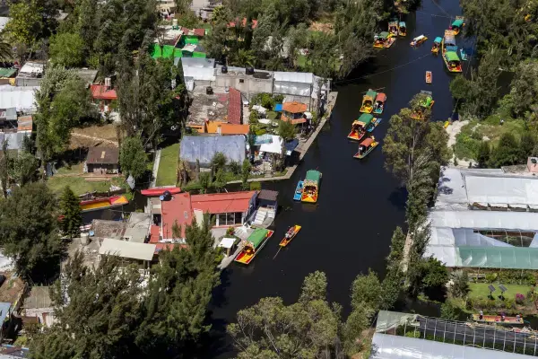Vista aérea dos canais de Xochimilco com trajineras coloridas navegando.