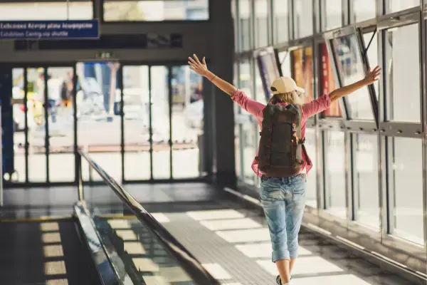 Mulher alegre em aeroporto com mochila nas costas