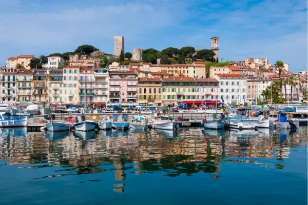 Porto antigo de Cannes com barcos coloridos e a torre do bairro Le Suquet ao fundo
