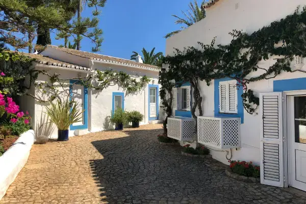Casas brancas com janelas azuis em rua de pedra no Algarve, Portugal.