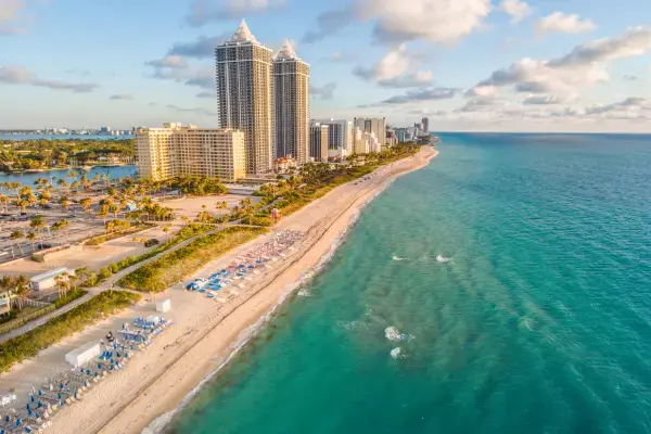 Praia de Miami com mar azul e prédios à beira-mar.