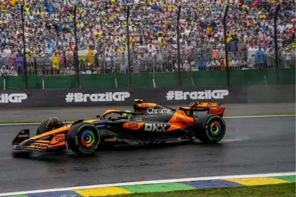 Carro de F1 na pista molhada de Interlagos com arquibancada lotada ao fundo