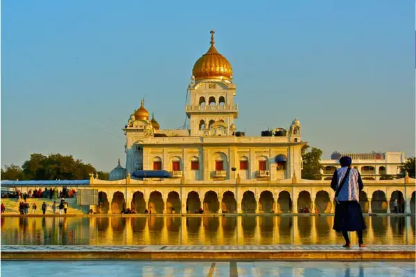 Templo Sikh Gurudwara Bangla Sahib em Nova Delhi com cúpula dourada refletida na água.