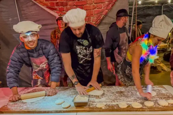 Voluntários com aventais e toucas de chef preparando comida em acampamento temático do Burning Man