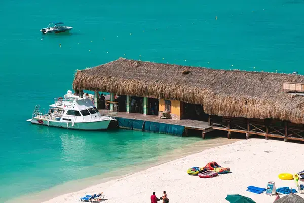 Bar de palha sobre o mar com barco de mergulho atracado em praia de Aruba
