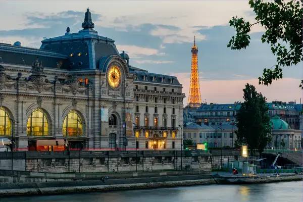 Musée d'Orsay iluminado ao entardecer com Torre Eiffel ao fundo, Paris