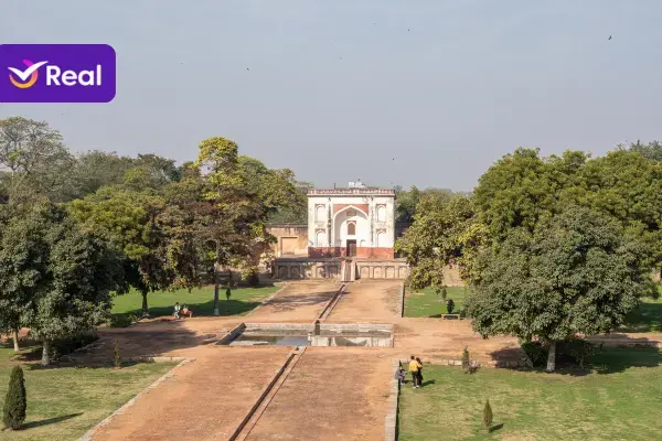 Estrutura histórica de arquitetura mogol cercada por gramados verdes e árvores.