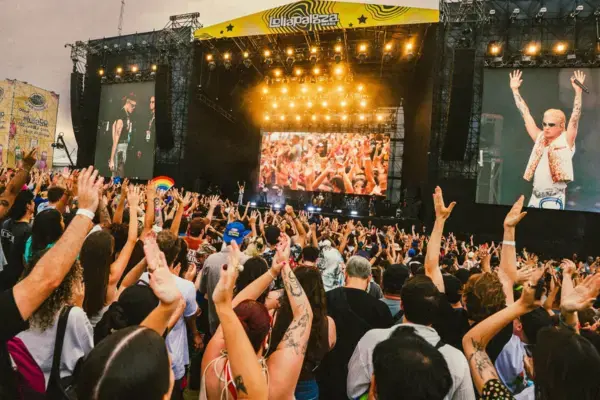Público assistindo show no Lollapalooza Brasil, com mãos levantadas em frente ao palco principal durante apresentação noturna.