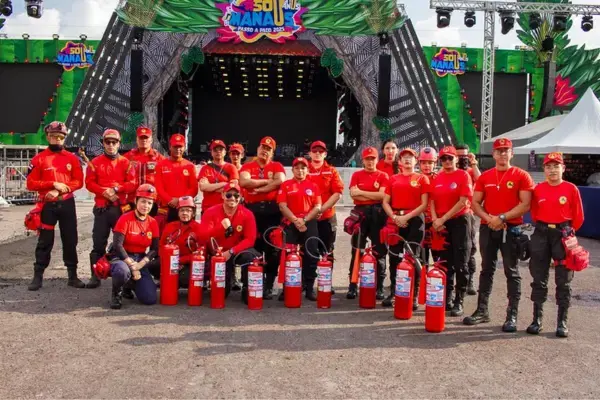 Equipe de bombeitos posando em frente ao palco do Sou Manaus com extintores de incêndio.