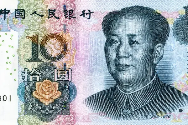 Close-up detalhado da face frontal de uma cédula de 10 Yuan da moeda chinesa (Renminbi). À direita, destaca-se o retrato de Mao Zedong, e à esquerda, o numeral '10' sobreposto a uma ilustração de uma rosa estilizada e padrões de segurança intrincados em tons de azul, rosa e verde. No topo, lê-se o nome do Banco Popular da China em caracteres chineses.