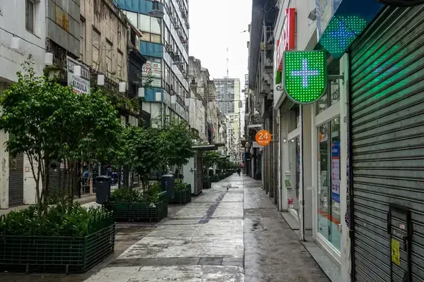 Fachada de farmácia europeia com sinalização iluminada de cruz verde