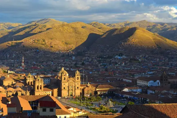 Vista panorâmica do centro histórico de Cusco com a Catedral e montanhas ao fundo ao entardecer