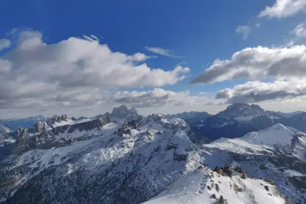 Vista panorâmica dos Alpes italianos cobertos de neve sob céu azul, cenário de montanhas que receberão provas das Olimpíadas de Inverno 2026.