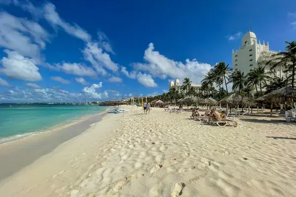 Faixa de areia branca e guarda-sóis de palha na praia de Palm Beach em Aruba.