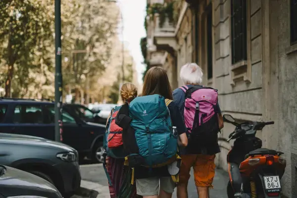 Família caminhando com mochilas por rua durante viagem internacional