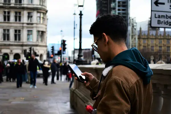 Pessoa consultando o celular em rua de cidade durante uma viagem